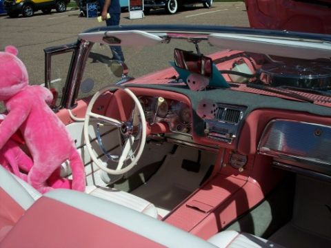 1972 Ford Ranchero - The vibrant pink interior of a convertible features a large stuffed animal and fuzzy dice hanging from the rearview mirror.