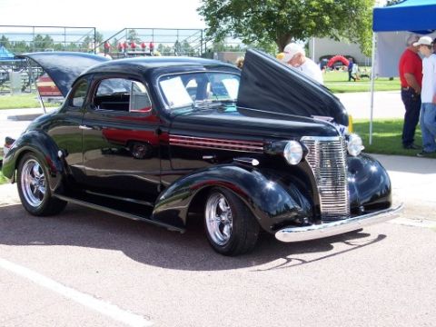 1972 Ford Ranchero - A black 1937 coupe is displayed with its hood open, revealing the engine bay and custom wheels.