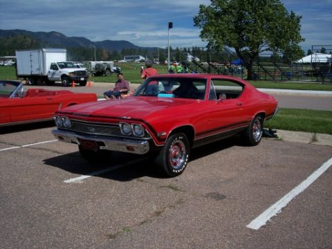 1972 Ford Ranchero - A red 1969 Chevrolet Chevelle coupe is parked in a lot, with another red car to its left.