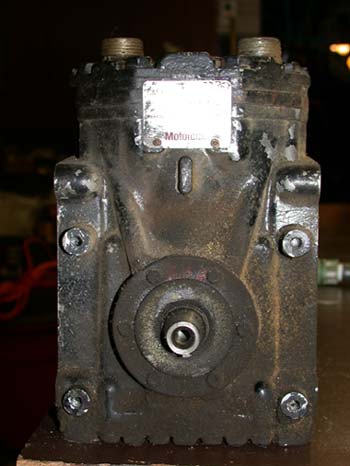 1996 Ford Bronco - Front-end view of a heavily soiled York-style piston compressor standing on a bench, showing the clutch mounting hub and splined shaft snou…