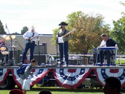 1972 Ford Ranchero - A band performs live music on an outdoor stage decorated with patriotic bunting.
