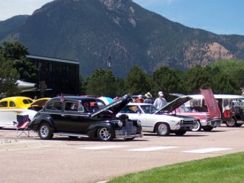 1972 Ford Ranchero - A collection of vintage automobiles are displayed outdoors with their hoods open, under a large mountain.