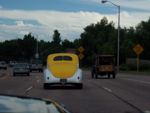 1972 Ford Ranchero - A vintage car with a yellow top and white body drives on a highway alongside modern vehicles.