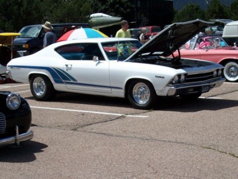 1972 Ford Ranchero - A white coupe with distinctive blue racing stripes is displayed with its hood open, revealing the engine bay.
