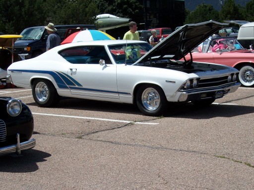 White 1969 Chevelle with blue stripes and open hood at a car show