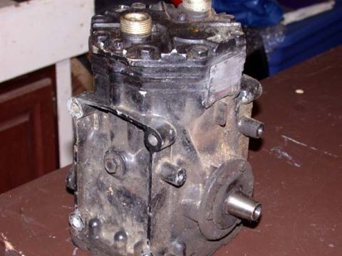 1996 Ford Bronco - A grimy, oil-stained York-style piston compressor sitting on a workbench before cleanup, with brass service fittings threaded into the top…