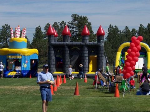 1972 Ford Ranchero - An outdoor event features inflatable attractions like a bouncy castle and a cake-themed play area, with people gathered on the grass.