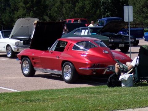 1972 Ford Ranchero - A red 1963 Chevrolet Corvette Sting Ray coupe is parked at an outdoor car show.