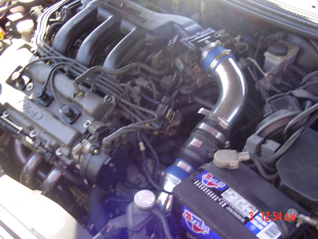 Engine bay of a car with blue aftermarket intake piping