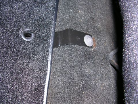 1996 Ford Probe - Close-up of a bracket attached to the carpeted floor of a car's interior.