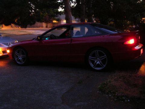 1996 Ford Probe - A red 1996 Ford Probe is parked outside at twilight, with its lights on.