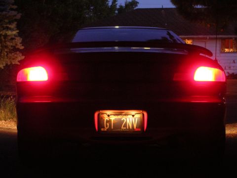 1996 Ford Probe - The rear of a car is illuminated by its brake lights at dusk, with a license plate visible.