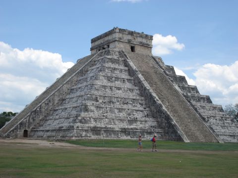 1991 Ford Bronco - The iconic El Castillo pyramid stands tall under a cloudy blue sky, with two visitors walking on the grassy foreground.