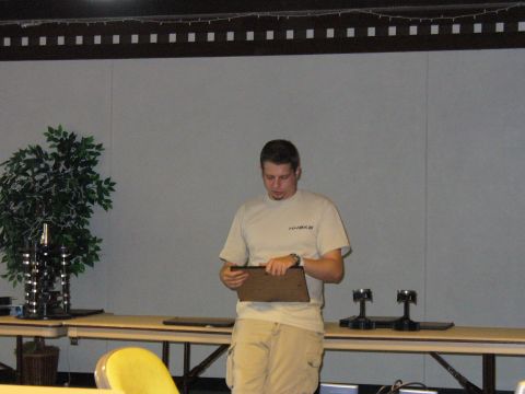 1991 Ford Probe - A man stands holding a clipboard in front of a large screen, with a potted plant and tables visible.