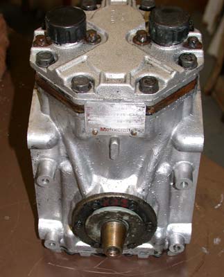 1996 Ford Bronco - A bare cast-aluminum York-style piston air conditioning compressor standing upright on a workbench, shown from the drive end with the expos…