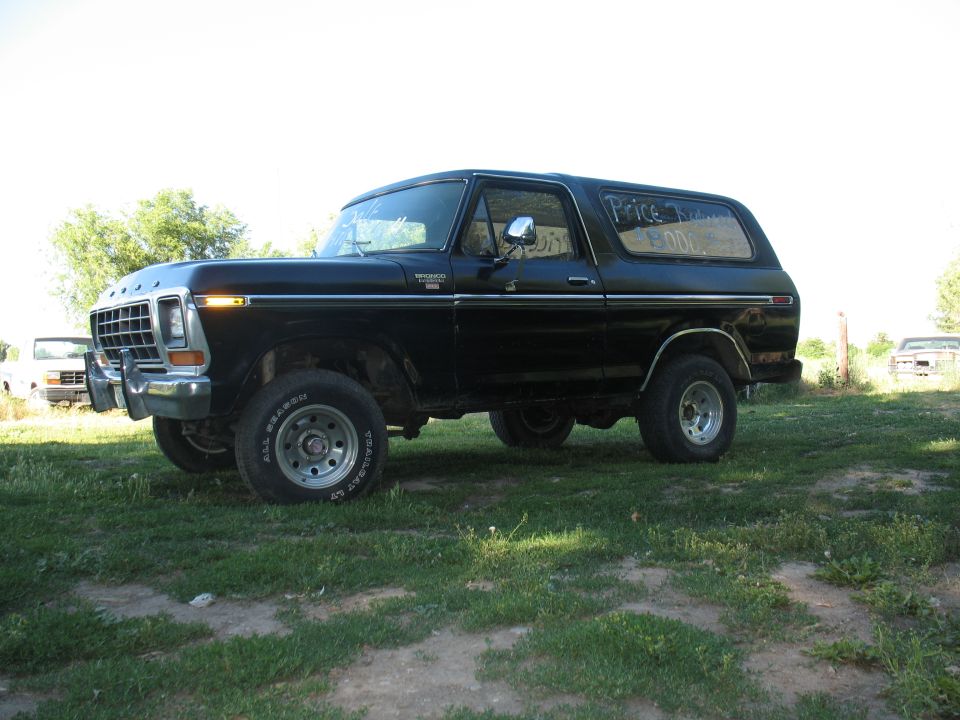 Black Ford Bronco in profile on grass with price soaped on the rear side window