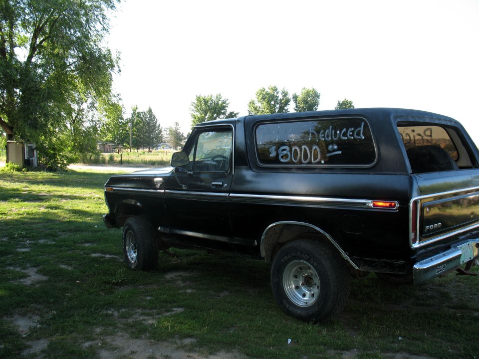 Black lifted Ford Bronco, side view, 'Price Reduced $8000' on rear window
