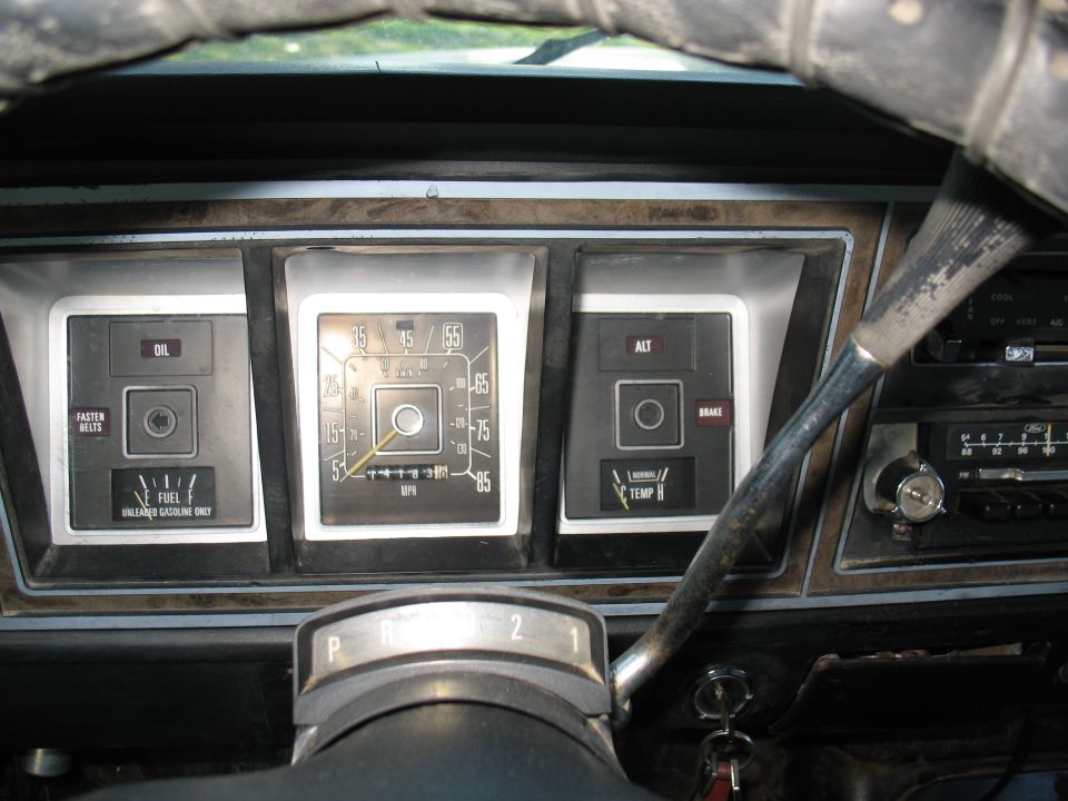 Faded 1970s Ford truck gauge cluster and woodgrain dash from driver's seat