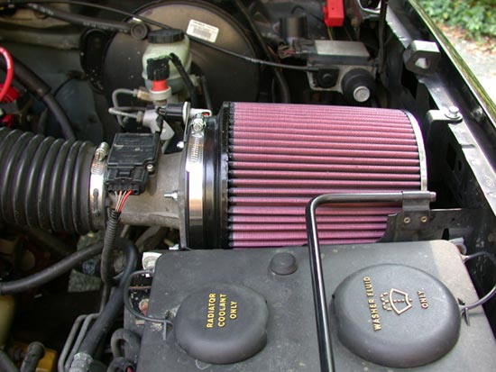 Red cone air filter on chrome intake tube with MAF sensor in a truck engine bay