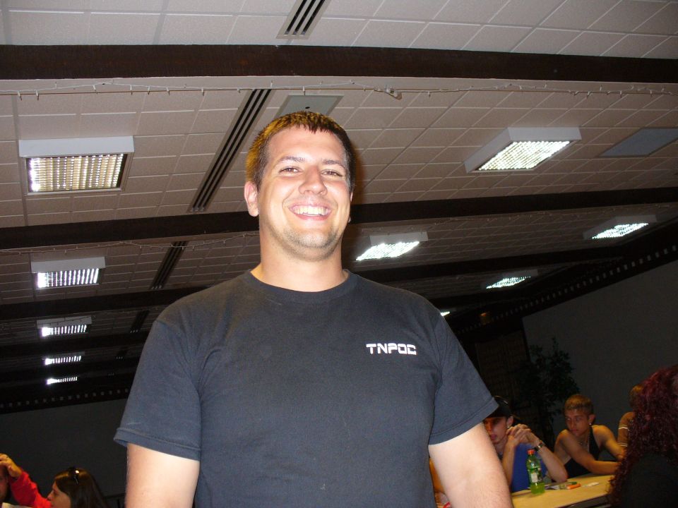 Man in black t-shirt with TNPOC logo, smiling
