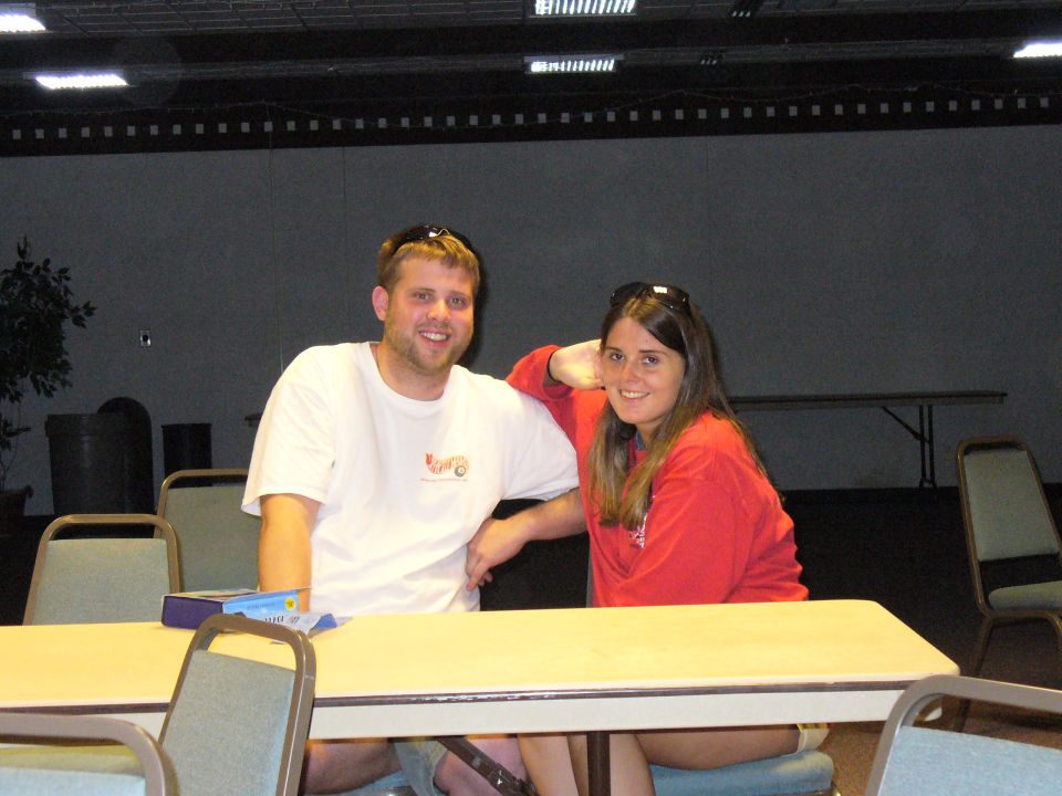 guy in white t-shirt and girl in red sweatshirt sitting at a table