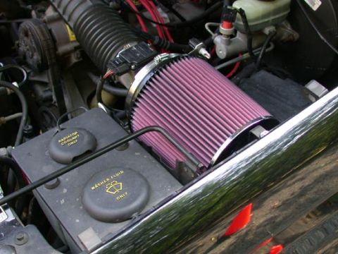 1996 Ford Bronco - Engine bay detail showing a red K&N-style conical cone air filter mounted to a chrome intake tube, replacing the factory airbox. The black…