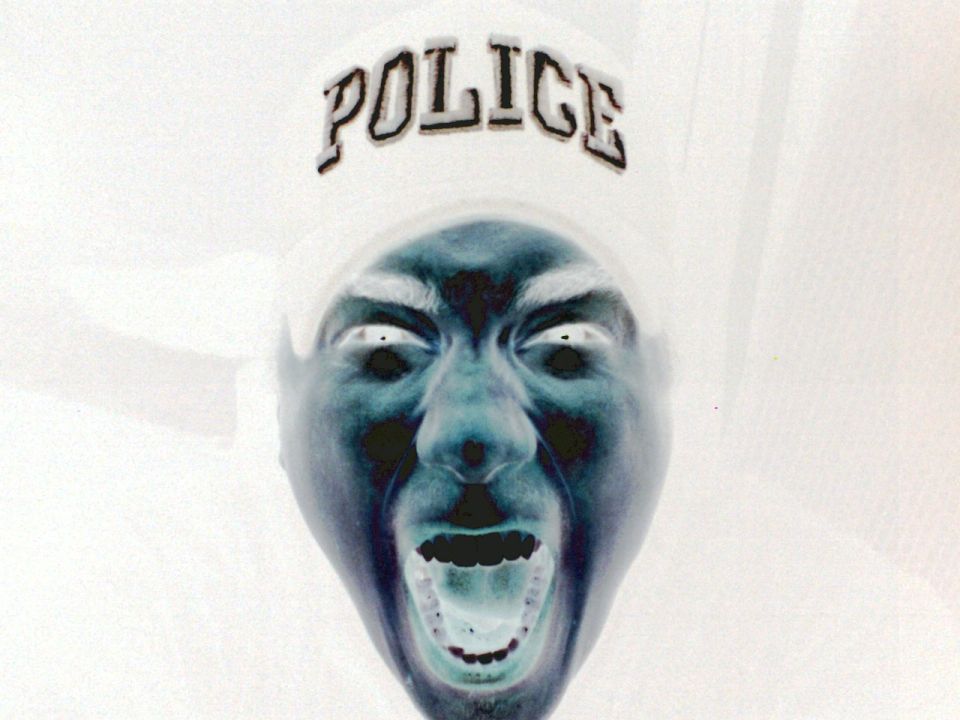 Inverted image of a person's face with mouth open, wearing a hat with the word POLICE on it