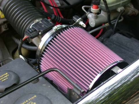 1996 Ford Bronco - Close-up of a red pleated conical air filter clamped to a chrome intake elbow in an engine bay, with the mass-air sensor connector and wiri…