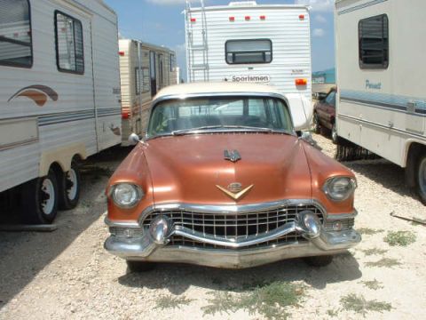 1972 Ford Ranchero - Front view of an orange sedan, possibly a 1955 Cadillac, parked between RVs.