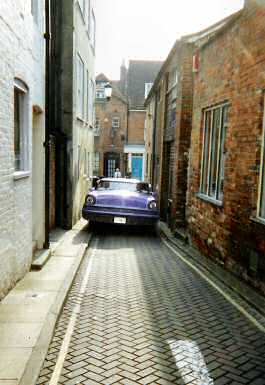 1972 Ford Ranchero - A purple 1972 Ford Ranchero is parked in a tight alleyway between brick buildings.