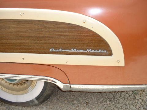 1972 Ford Ranchero - Close-up of a vintage car's side panel, showing wood grain and a chrome emblem.