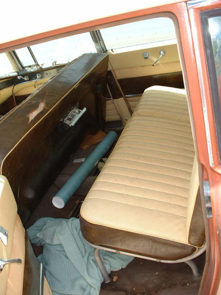 1972 Ford Ranchero - The interior of an older vehicle shows tan bench seats and brown door panels, with a blue poster tube and a light blue blanket on the floor.