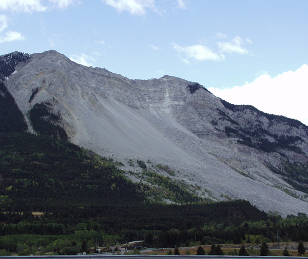 Mountain landscape with landslide debris and trees. "SUPERMOTORS www.supermotors.net" text at bottom right