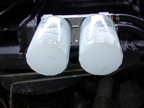 1996 Ford Bronco - Two white NAPA Silver spin-on filters mounted side by side on a bracket in a greasy engine bay, with part numbers printed on the canisters.…