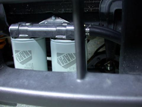 1996 Ford Bronco - Close-up of a twin oil-filter setup, with two white NAPA Gold 21515 filters threaded onto a polished aluminum dual-filter mount and connect…