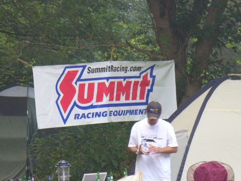 1991 Ford Probe - A banner for Summit Racing Equipment hangs in front of tents, with a person standing nearby.