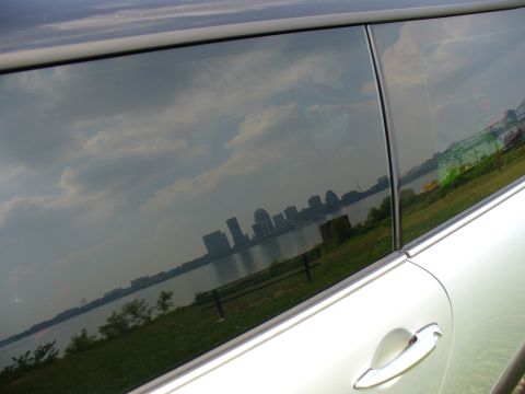 1991 Ford Probe - Reflection of a city skyline and clouds in the tinted window of a white car.