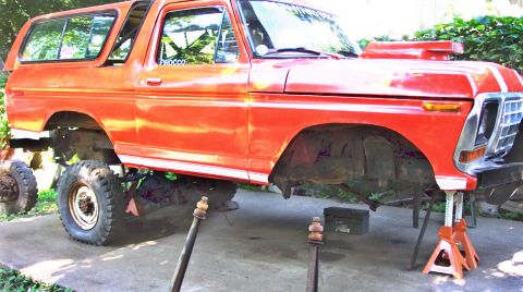 1978 Ford Bronco - This orange SUV is on jack stands, appearing to be undergoing maintenance or modification.