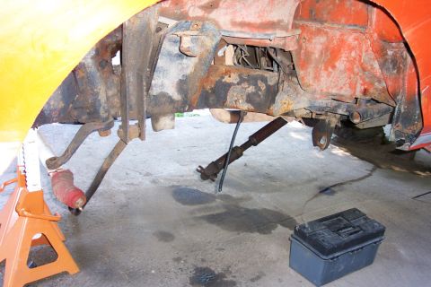 1978 Ford Bronco - This photo shows the heavily rusted frame and suspension components of a vehicle, supported by jack stands.