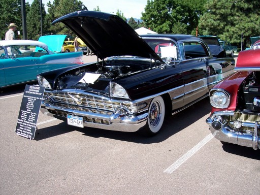 Black 1956 Cadillac Coupe de Ville with hood open, parked next to a red car