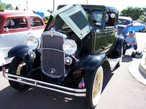 1972 Ford Ranchero - A dark green and black 1930s Chevrolet coupe is displayed with its hood open at a car show.