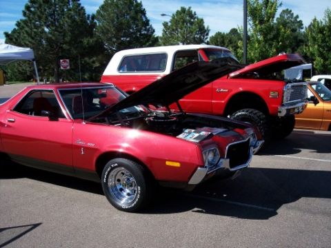 1972 Ford Ranchero - Two vehicles, a 1972 Ford Ranchero and a lifted Chevrolet K5 Blazer, are displayed at a car show with their hoods open.