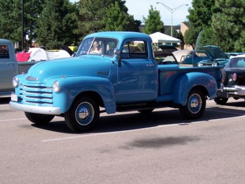 1972 Ford Ranchero - A bright blue 1950 Chevrolet pickup truck is parked at a car show, with other vehicles visible in the background.