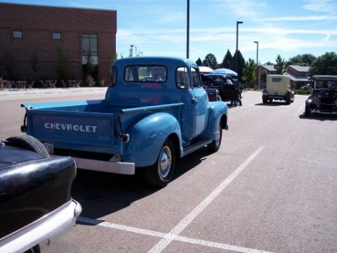1972 Ford Ranchero - A blue Chevrolet pickup truck is seen from the rear at a car show with other vehicles present.