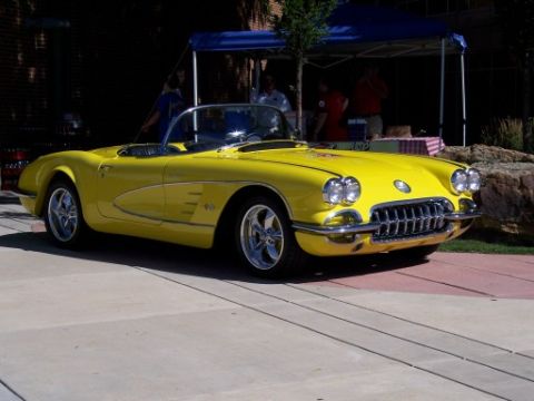 1972 Ford Ranchero - A bright yellow 1958 Chevrolet Corvette convertible is parked on a paved area, with a tent and people visible behind it.