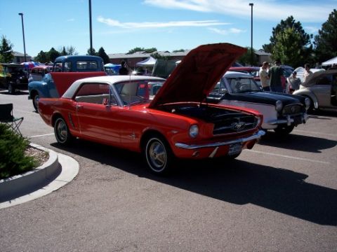 1972 Ford Ranchero - A red 1965 Ford Mustang convertible is displayed with its hood open at a car show.