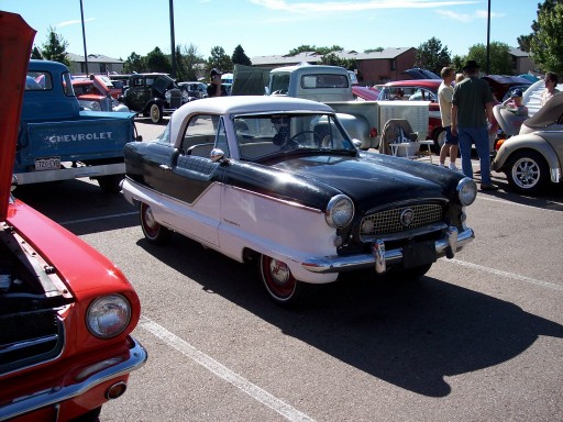 Black and white Nash Metropolitan parked at a car show, other vehicles visible