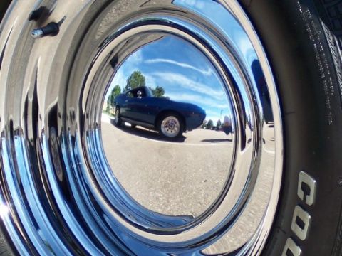 1972 Ford Ranchero - Reflection of a blue 1972 Ford Ranchero in a shiny chrome hubcap at a car show.