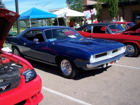 1972 Ford Ranchero - A blue 1970 Plymouth Barracuda is displayed at a car show with other vehicles.