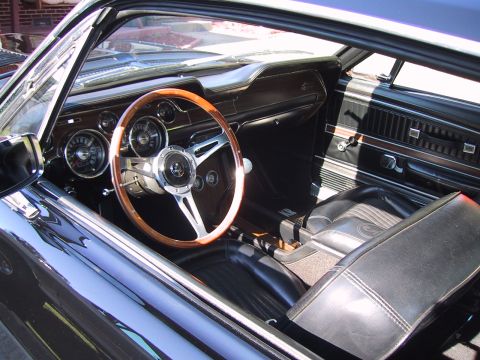 1968 Shelby GT500 - The interior of a 1968 Shelby GT500 features a wood-rimmed steering wheel and black leather seats.